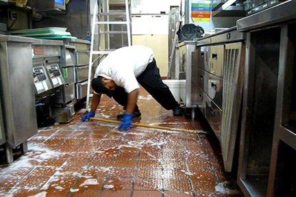 Professional team performing restaurant cleaning in kitchen area