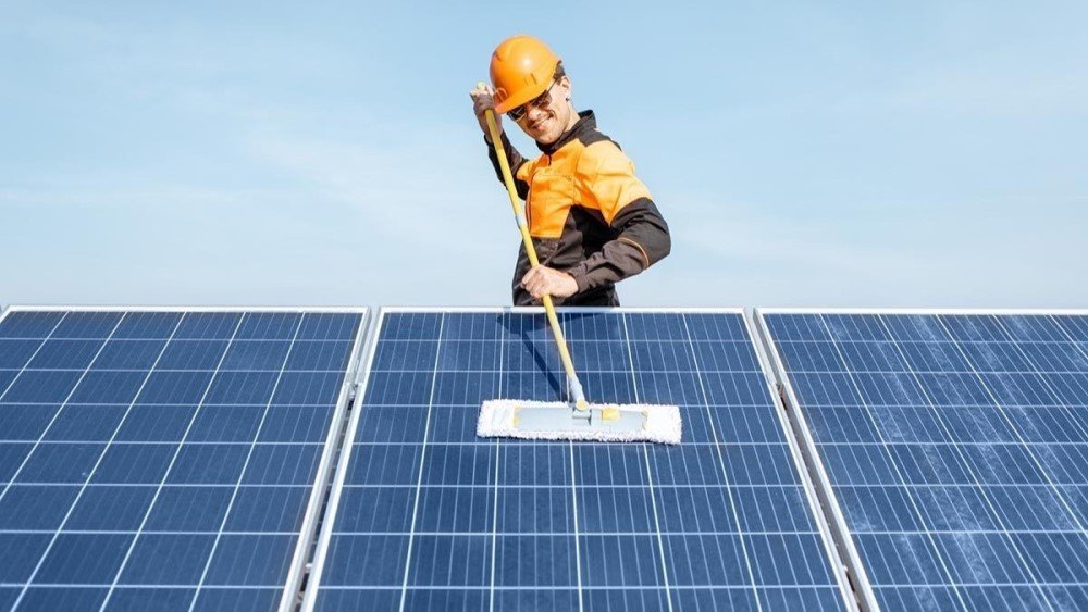 Technician performing solar panel cleaning on a rooftop using professional tools