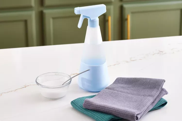DIY cleaning solutions consisting of a cup, a spray bottle and a mopping towel 